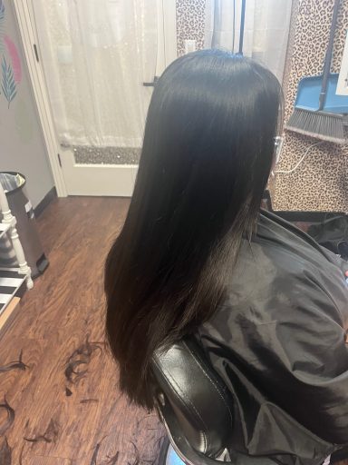 Long, straight black hair cascading down from a seated person's back in a salon.